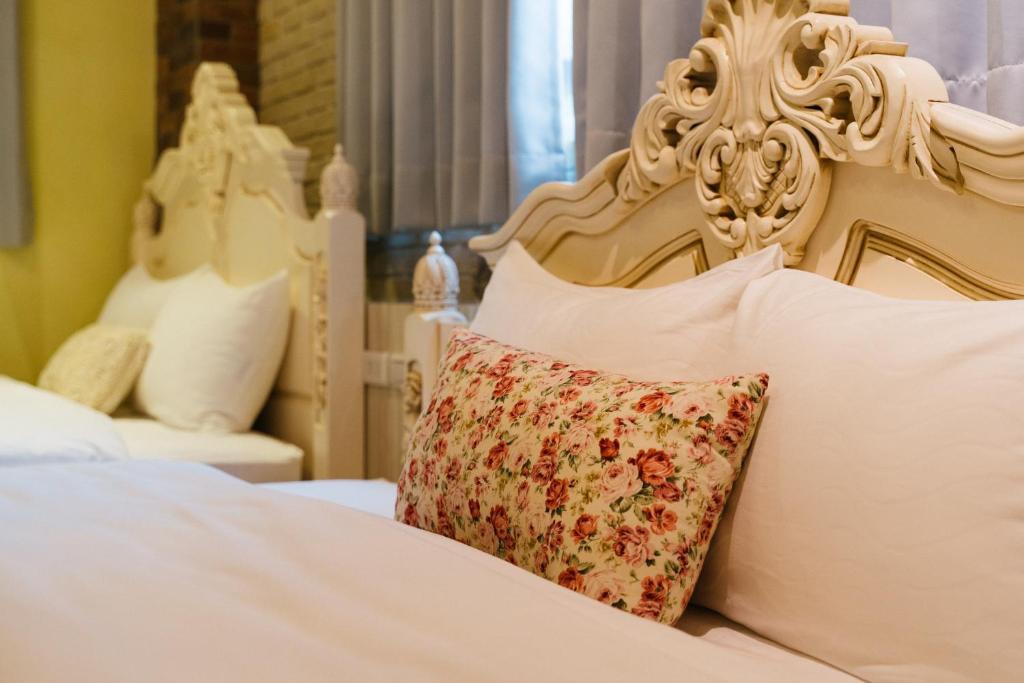a white bed with a flower pillow on it at Brulee's Done in Dongshan