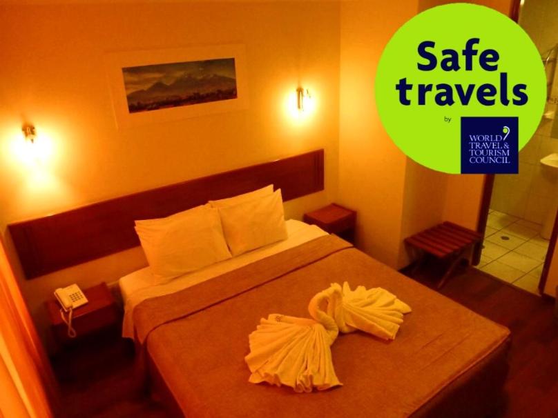 una habitación de hotel con una cama y un cartel que dice que viaje seguro en Hostal Qoyllurwasi, en Arequipa