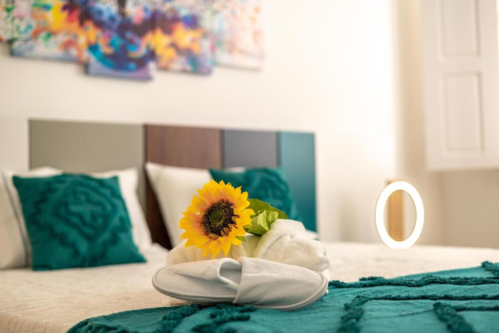 a towel with a sunflower on a bed with a mirror at FERREIRA'S HOUSE Guimarães in Guimarães