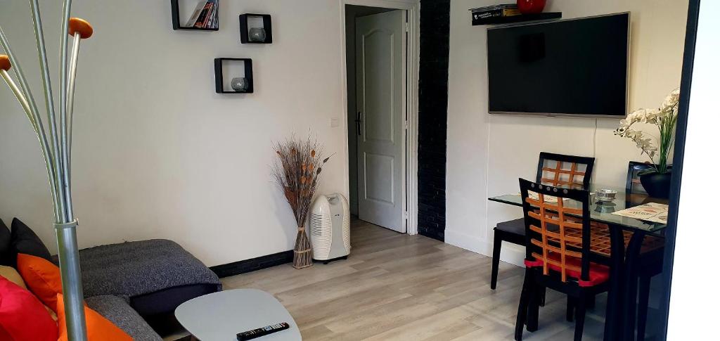 a living room with a table and a television on a wall at 84 ėme rue in Vitry-sur-Seine