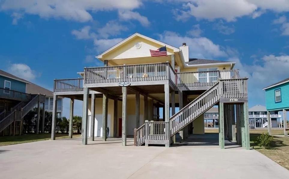 una casa con una veranda con una bandiera americana sopra di Lemoncello Home a Bolivar Beach