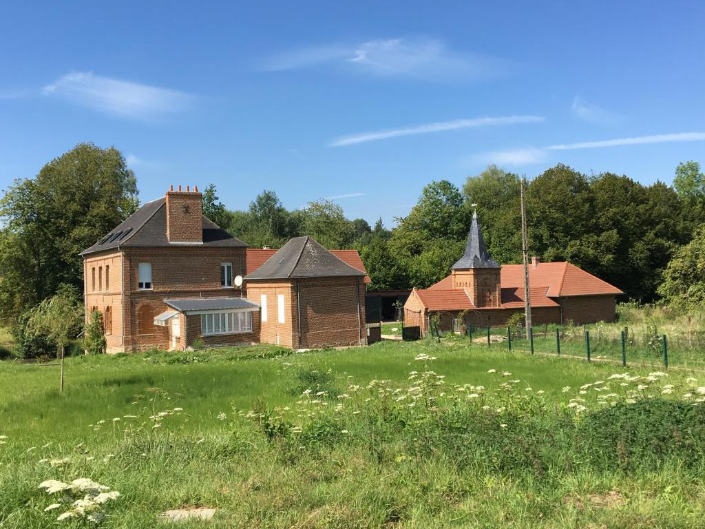 una vecchia casa in un campo vicino a un prato di chambres d'hôtes et Gîte Le Moulin Sainte Marie a Estrée-Wamin