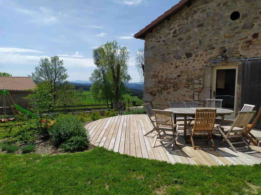 a wooden deck with a table and chairs next to a building at Gîte Riotord, 5 pièces, 9 personnes - FR-1-582-292 in Riotord