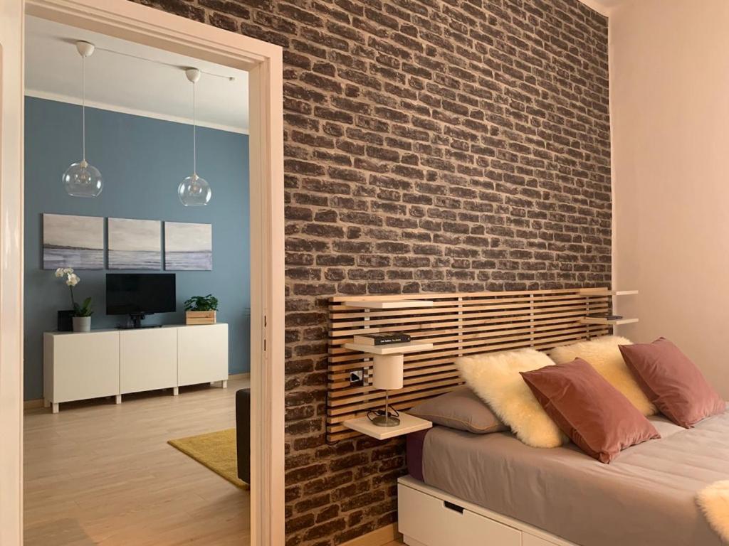 sypialnia z ceglaną ścianą i łóżkiem w obiekcie Camozzi Central Apartment w Bergamo