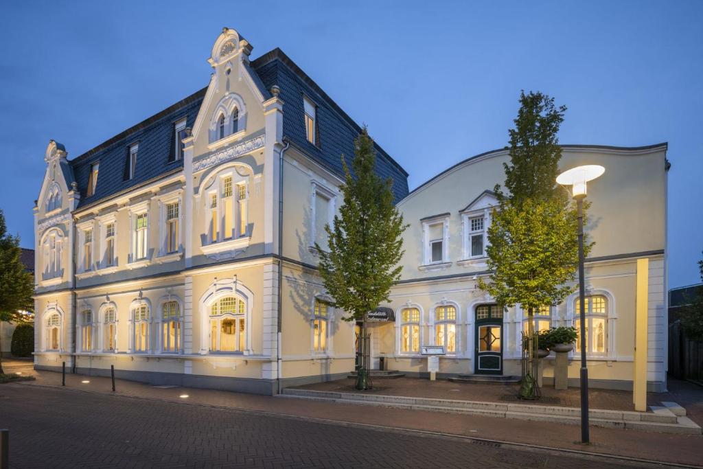 a large white building with trees in front of it at Visbek Hotel Stüve in Visbek