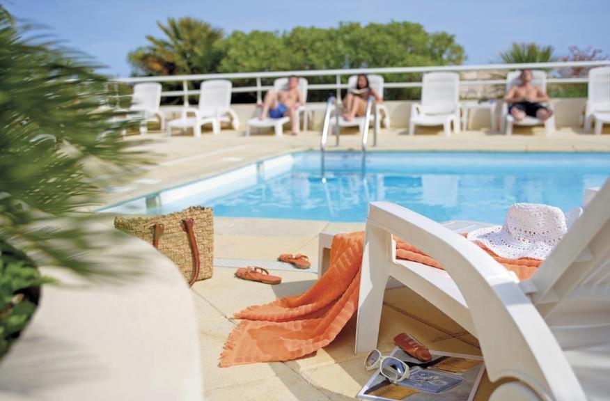 une piscine avec des chaises et des personnes assises sur un balcon dans l'établissement Monaco à 300m du Casino - Grand Studio avec Piscine, à Beausoleil