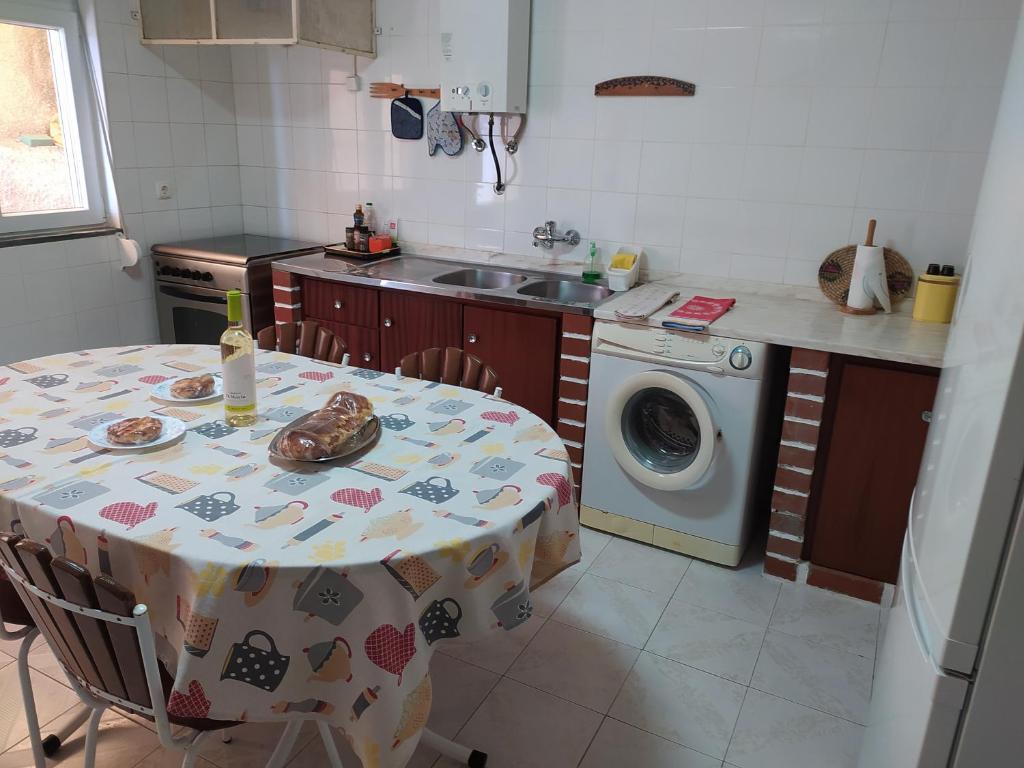 a kitchen with a table and a washing machine at Casa Eira do Povo in Vale de Colmeias