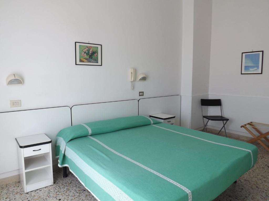 リミニにあるHotel Villa Domizianaのベッドルーム1室(緑のベッド1台、椅子2脚付)