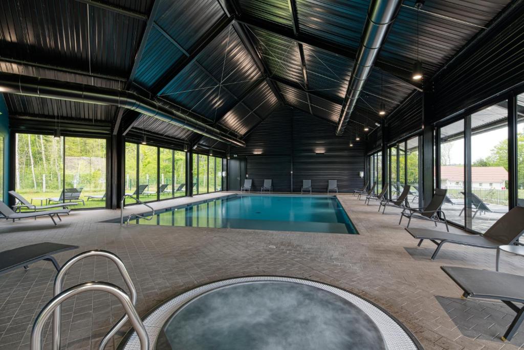 an indoor swimming pool with chairs and a large room with windows at Hôtel Lac d'Orient in Mesnil-Saint-Père