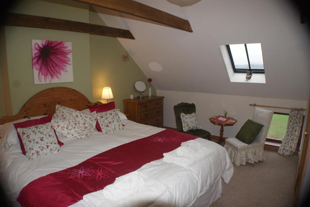 a bedroom with a large bed with red and white pillows at Knockaloe Beg Farm in Patrick