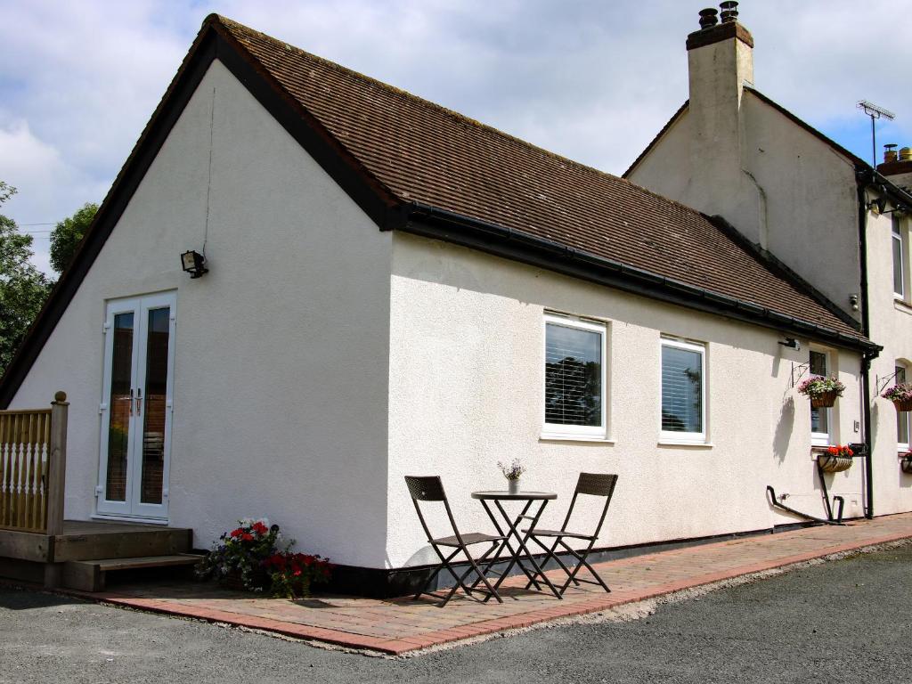 una casa bianca con sedie e un tavolo di fronte ad essa di Lindens Annexe a Shrewsbury