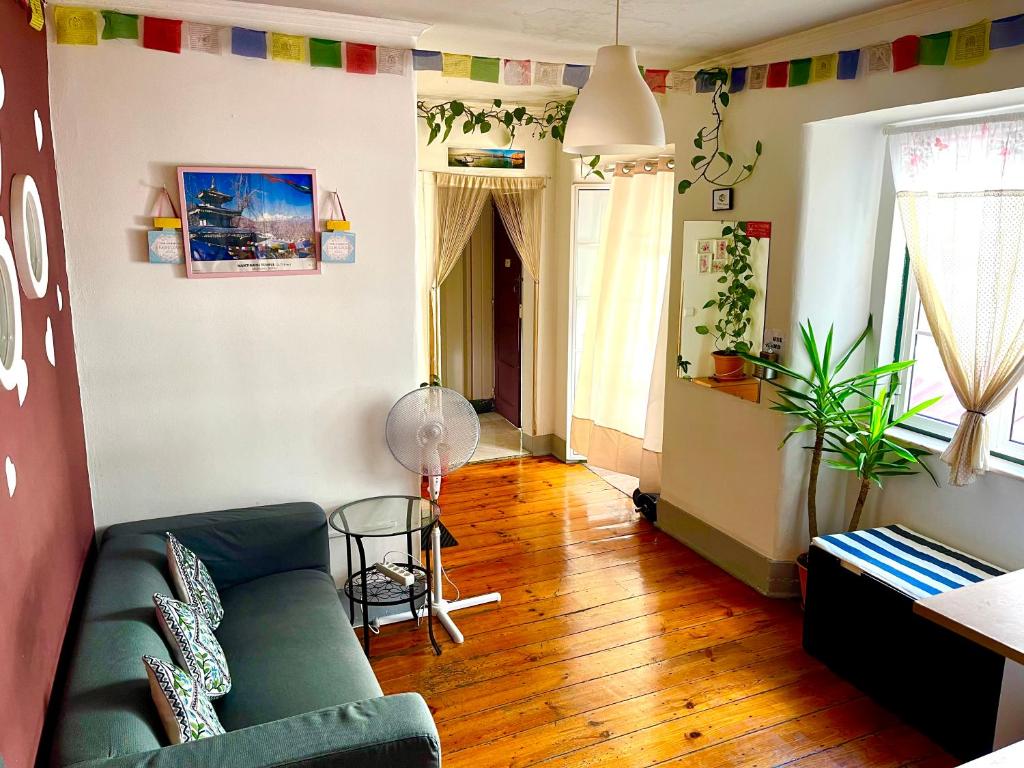 salon z zieloną kanapą i drewnianą podłogą w obiekcie Asian Everest House w Lizbonie