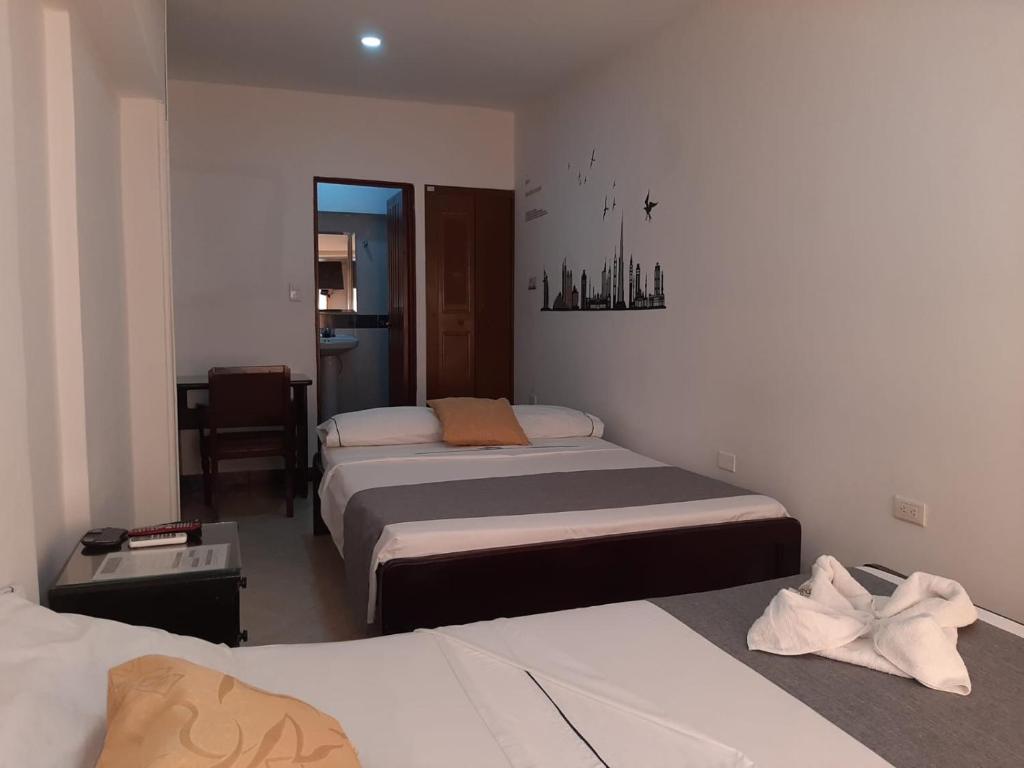 Hotel Neiva Providencia في نيفا: غرفة نوم بسريرين وطاولة ومرآة