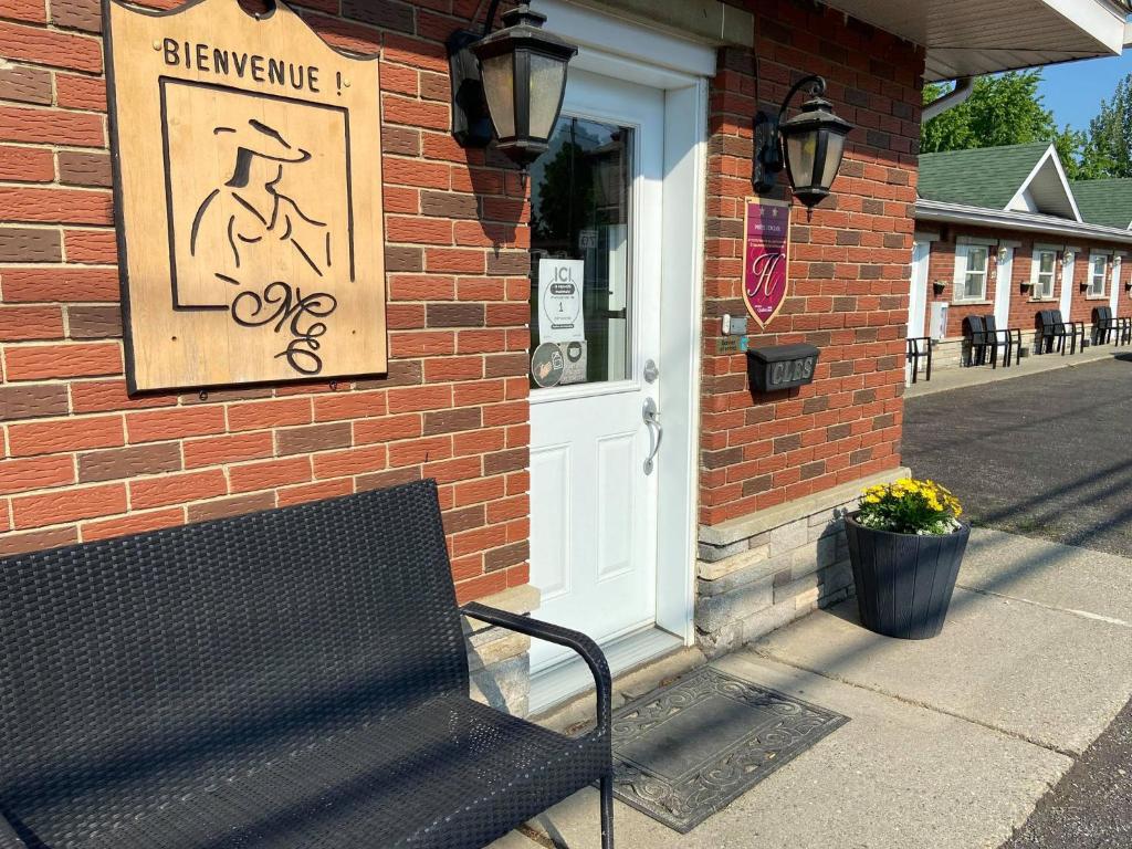 a black bench sitting outside of a building with a door at Motel Exquise in Coaticook