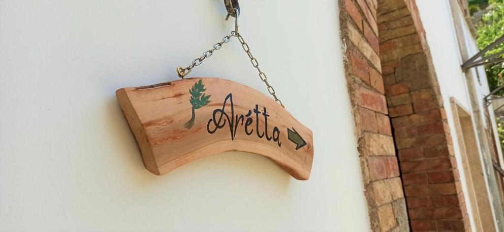 un cartello di legno appeso a un muro di Arétta: appartamento nel cuore di Itri a Itri