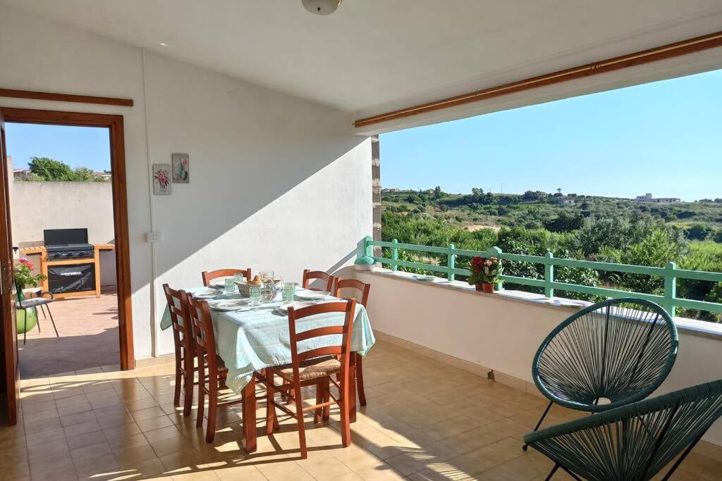 a dining room with a table and chairs on a balcony at La Terrazza sul Melograno - Magomadas in Magomadas