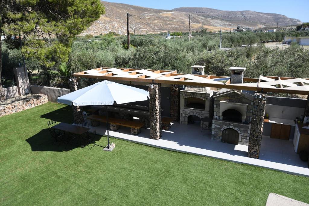an outdoor grill with a roof on a lawn at Orion Eco Suites in Karteros