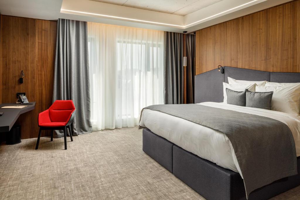 um quarto de hotel com uma cama grande e uma cadeira vermelha em Qosmo Brasov Hotel em Braşov