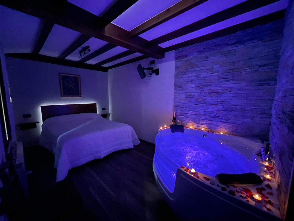 a bedroom with a bed and a tub with lights at La Era de Lario habitación con Jacuzzi in Lario