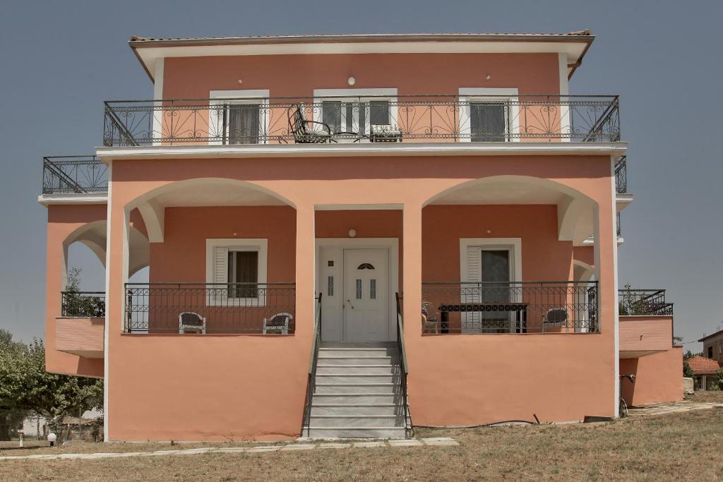 una casa rosa con porta bianca e balcone di Villa Ancient Olympia by PCL a Pelópion