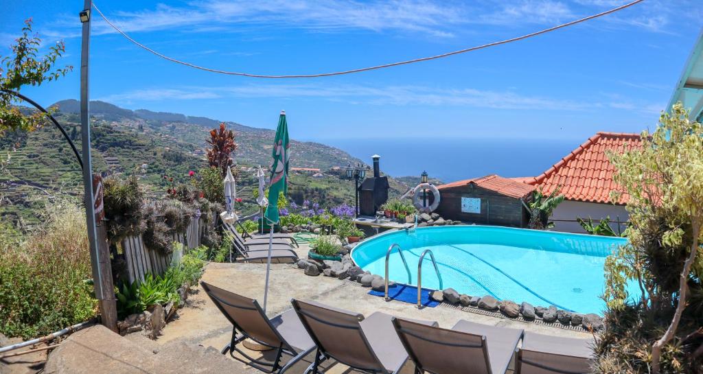 a house with a swimming pool and mountains in the background at Casas Tipicas Candelaria Tabua in Ponta do Sol