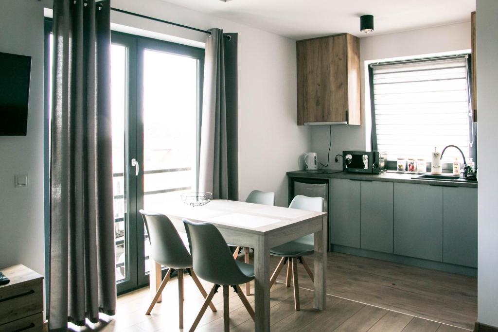 a kitchen with a white table and chairs and a window at Pokoje Marysia Mechelinki in Mechelinki