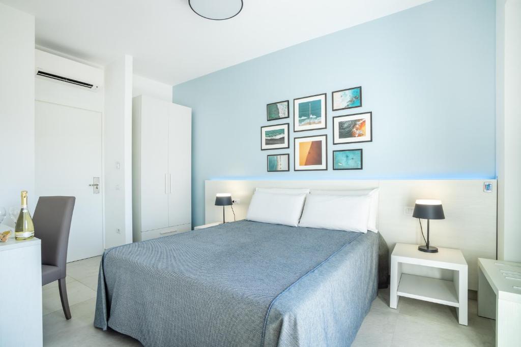 een witte slaapkamer met een blauw bed en een aantal foto's aan de muur bij J Rooms in Olbia
