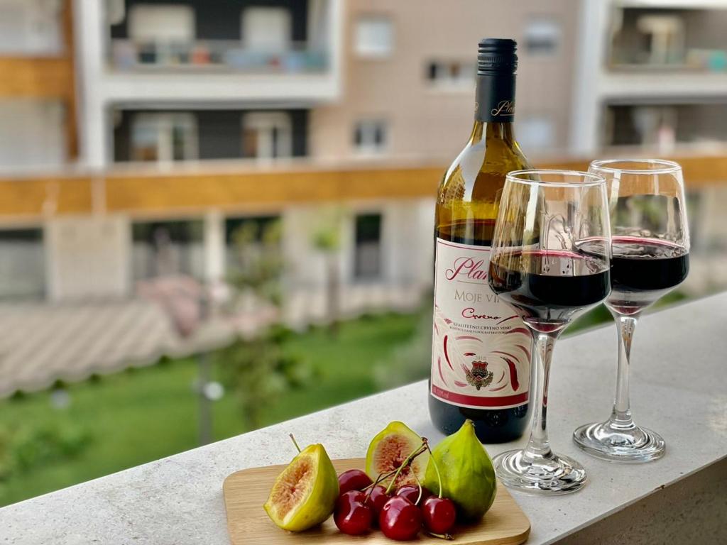 a bottle of wine and two glasses of cherries at Olive Square Apartment Budva in Budva