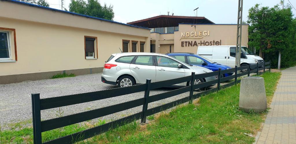 熱舒夫的住宿－ETNA - Hostel -Noclegi Rzeszów，两辆汽车停在大楼前的围栏旁边