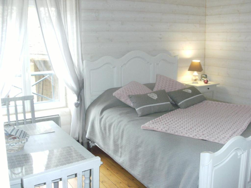 Un dormitorio con una cama blanca con almohadas y una ventana en jolie chambre dans ancien corps de ferme, en Bellengreville