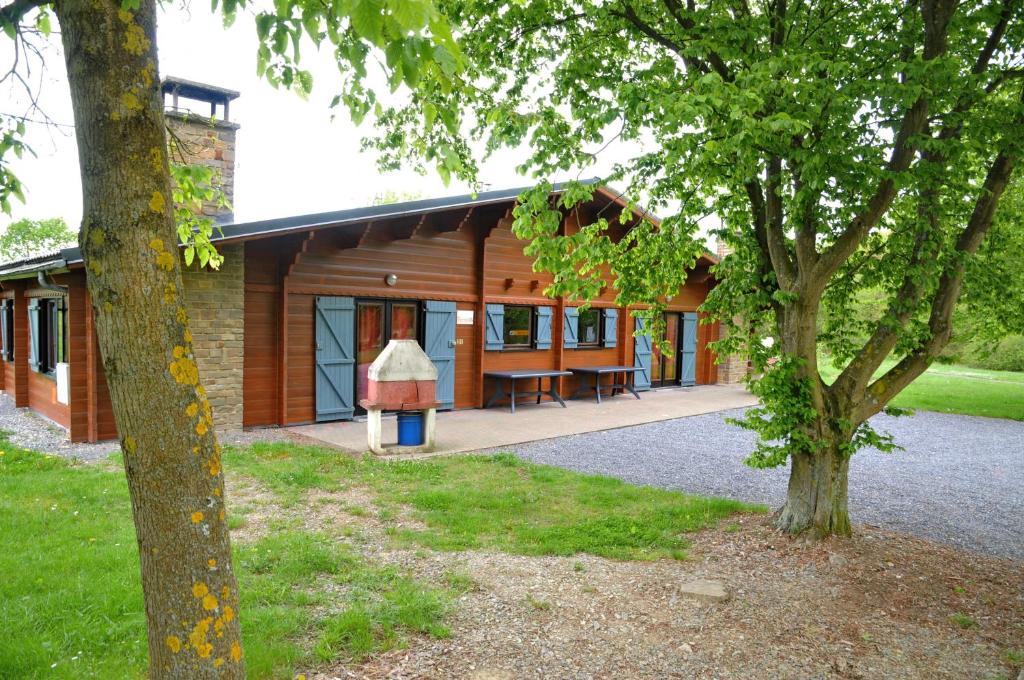 a log cabin with a porch and a tree at Gite L'unité in Hour