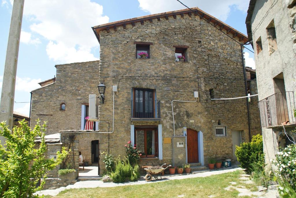 uma velha casa de pedra com uma bandeira em frente em L´estudi em El Meüll