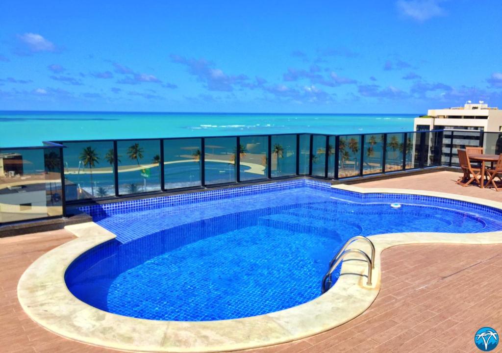 a swimming pool on top of a building with the ocean at Vacanze - Port Ville III in Maceió