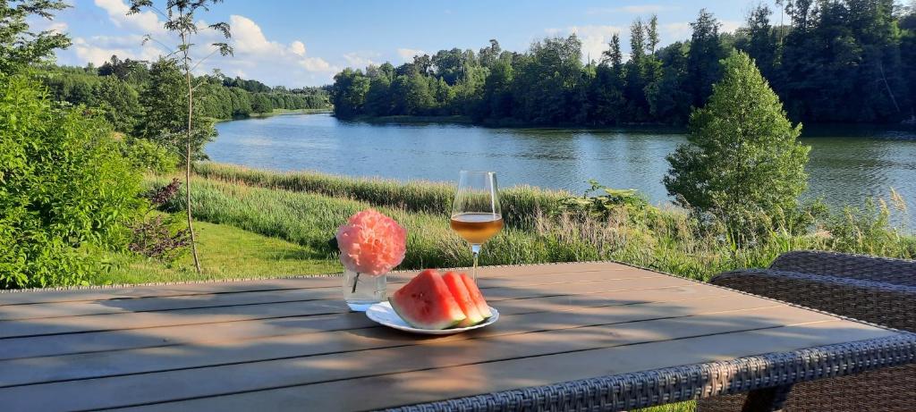 a picnic table with a glass of wine and a slice of watermelon at Spokojnia Ostróda in Ostróda