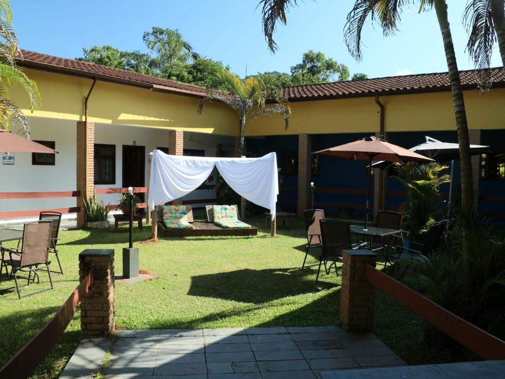 un cortile con sedie, tavoli e ombrelloni di Francis Hotel Pousada a Caraguatatuba