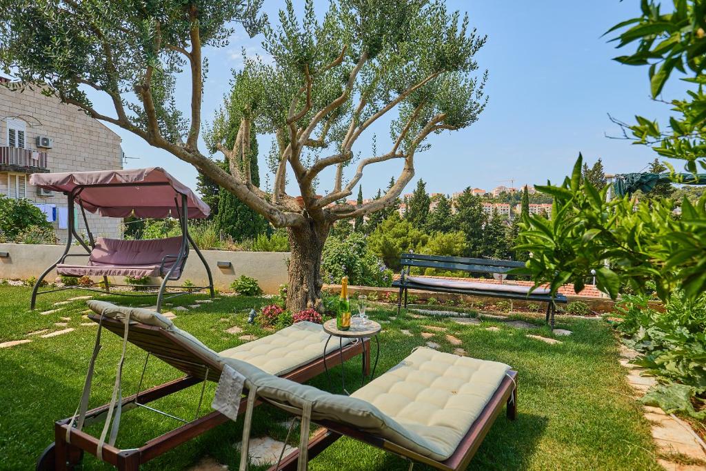 um jardim com um banco, uma mesa e uma árvore em Guest House Anica em Dubrovnik
