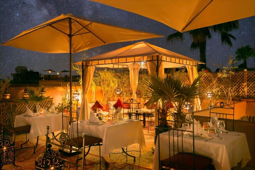 un restaurante con mesas y sombrillas por la noche en Arabian Riad Marrakech, en Marrakech