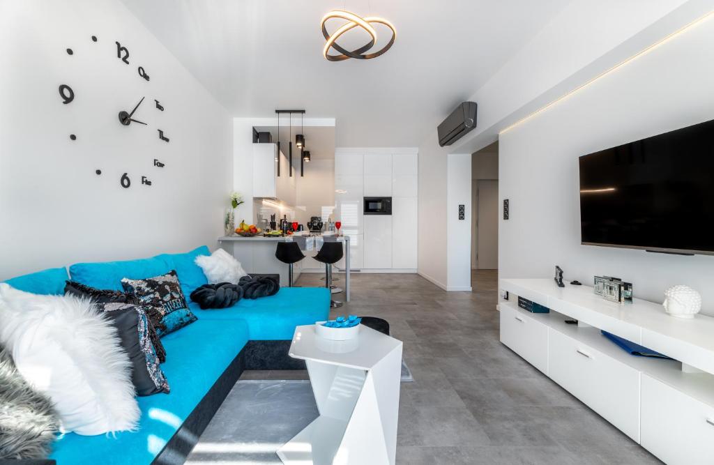 een woonkamer met een blauwe bank en een tv bij Leo Apartament Delux in Ustrzyki Dolne