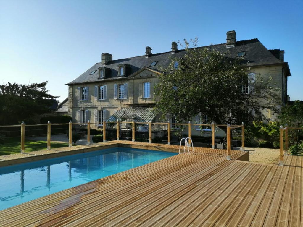 ein Haus mit einem Swimmingpool vor einem Haus in der Unterkunft Bed & Breakfast Chateau Les Cèdres in Bretteville-lʼOrgueilleuse