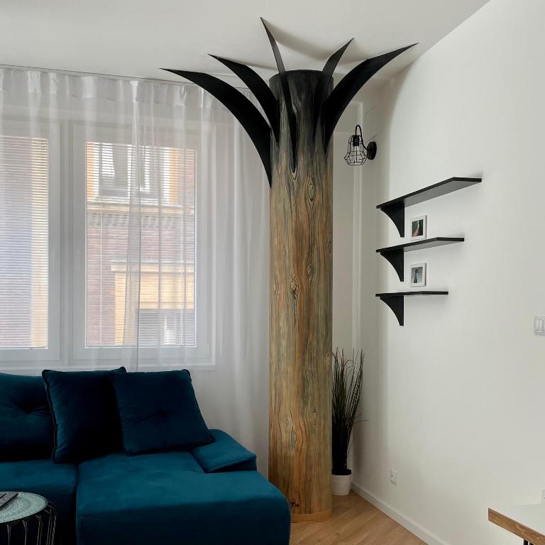 a living room with a blue couch and a tree at BeTree in Bratislava