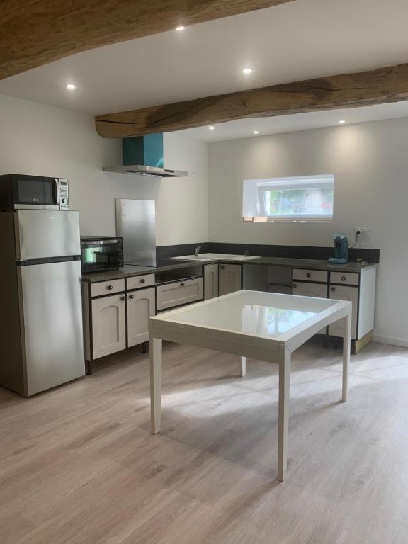 une cuisine avec une table au milieu dans l'établissement L’Estable du Pin, à Le Pin