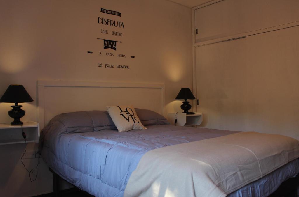 1 dormitorio con 1 cama con 2 lámparas y un cartel en la pared en La Quinta Mendoza en Mendoza