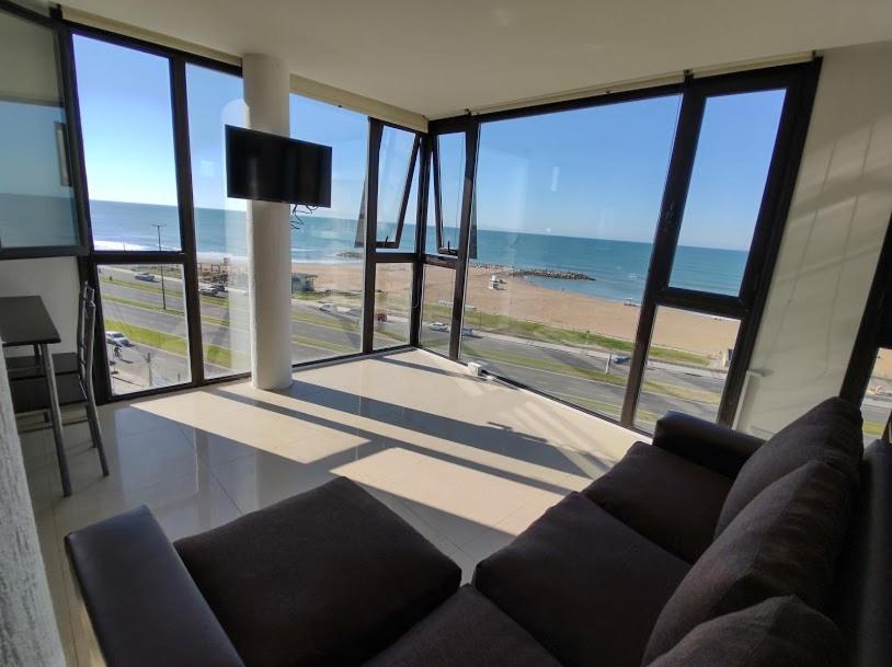 Frente al mar charlone في مار ديل بلاتا: غرفة معيشة مع أريكة وإطلالة على الشاطئ
