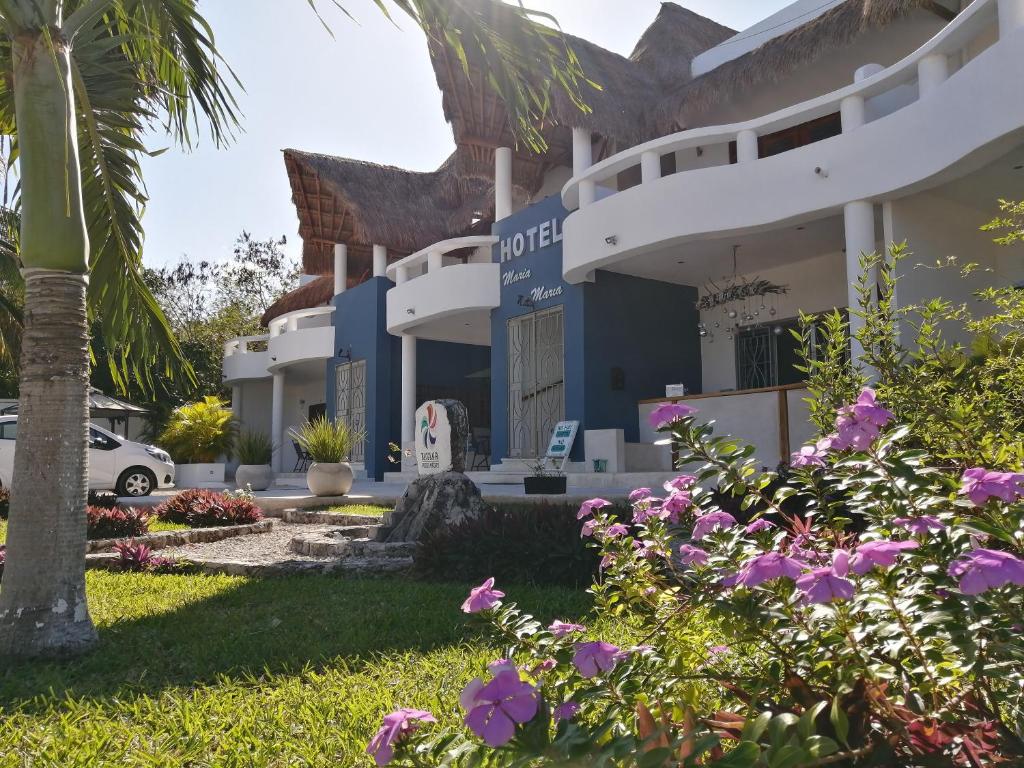 a large white house with trees and lawn chairs at Hotel Maria Maria in Bacalar