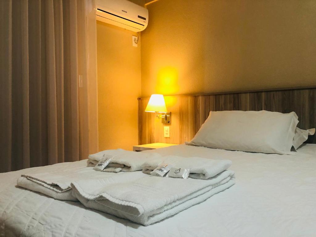 un letto con asciugamani bianchi in una stanza di Aquarius Flat Aptos e Suítes a Santa Cruz do Sul