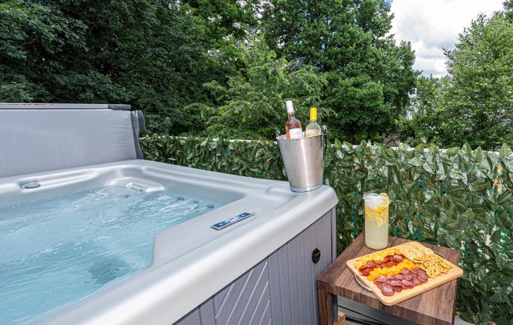 a hot tub with a tray of food and bottles of alcohol at Hot Tub WiFi Pool Gym Firepit Arcade in Kernersville