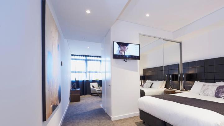 a bedroom with a bed and a tv on a wall at KOZYGURU Chatswood Luxury Studio NCH088-720 in Sydney
