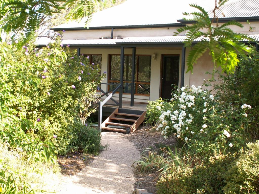ein kleines Haus mit einer Veranda und einigen Büschen in der Unterkunft Archery Road Estate in Rowland Flat