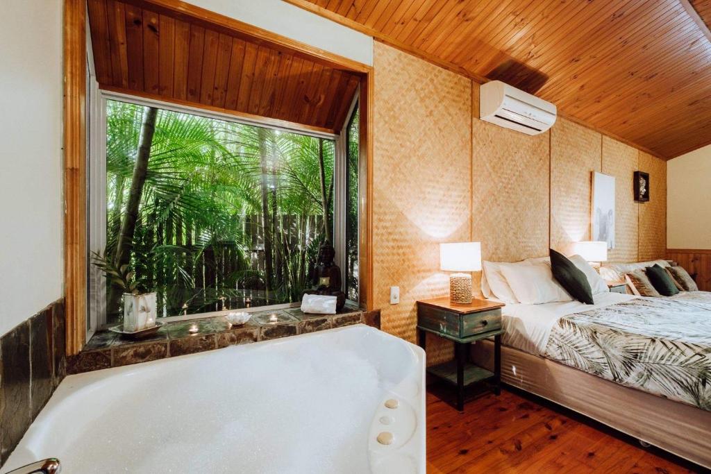 a bathroom with a tub and a bed and a window at Getaways at Byfield in Byfield