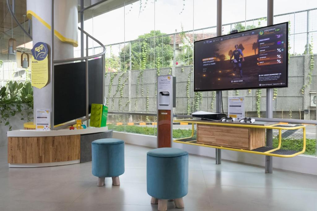 a room with a large tv and two blue stools at YELLO Hotel Kuta Beachwalk Bali in Kuta